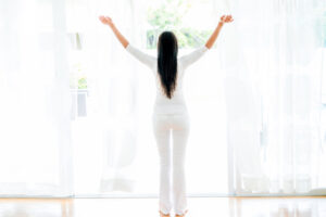 Woman opening the windows at home and enjoying some fresh air.