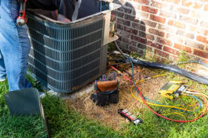 3 Tips to Prevent AC Breakdown During a Heat Wave. Photo of a black air conditioning unit installed outside of a brick home.