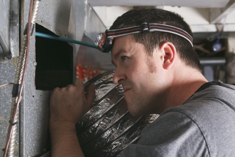 Why Is My Furnace Leaking Water? Photo of a technicial inspecting the ventilator looking for dust.