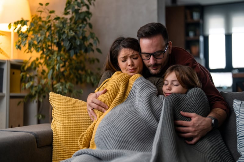 Why Isn’t My Furnace Heating My Entire Home? Family of three freezing in their home, huddled under blankets to keep warm.