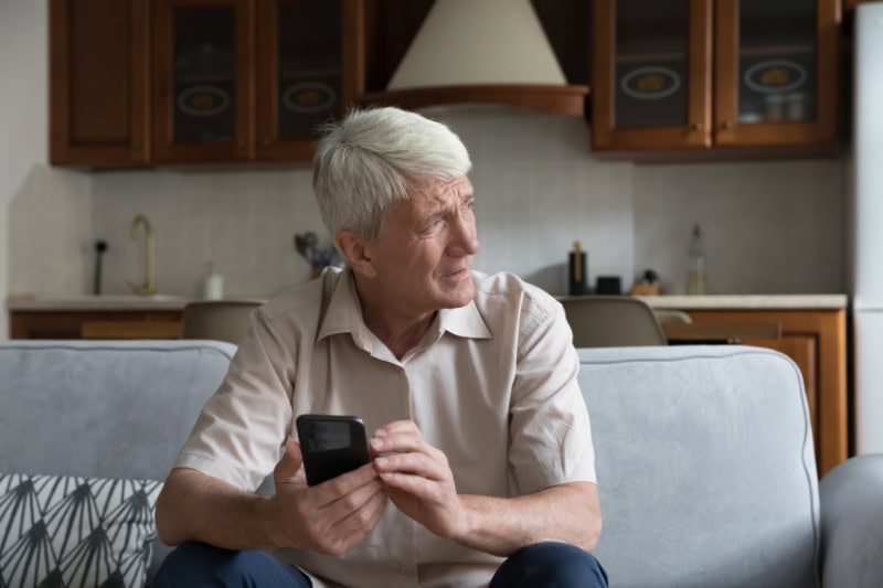 What’s That Smell Coming From My Furnace? Photo of a man sitting on his couch, looking out a window seemingly concerned.
