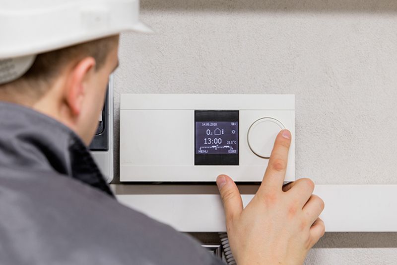 Image of a technician working with a thermostat. Why Schedule Air Conditioning Maintenance?