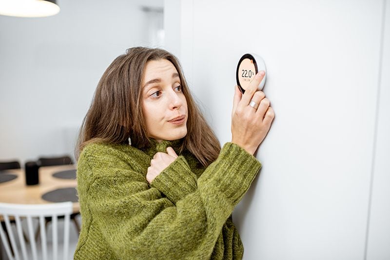 Why Is My Heat Pump Turning On and Off Frequently? - Woman Adjusts her Thermostat.