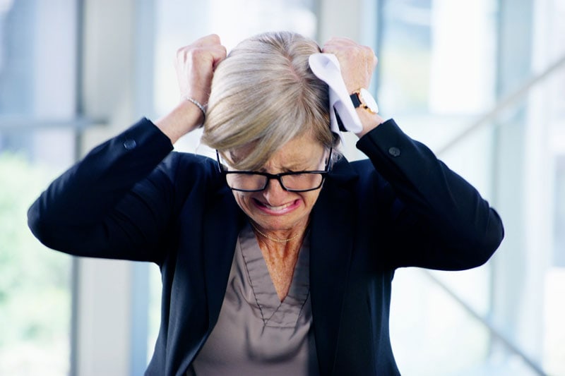 woman holding head in frustration, feeling overwhelmed.