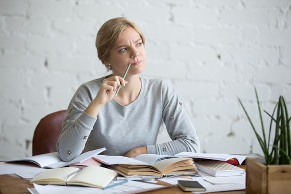 A woman ponders with papers on a table. What’s That Sound Coming From My Furnace?